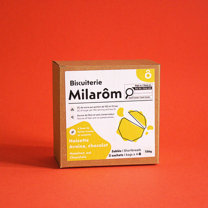 Cette image montre sur un fonds rouge notre boîte de 12 biscuits sablés à la noisette, avoine et chocolat ; nous utilisons dans nos recettes des farines de noisette et d'avoine, ce qui en fait un produit pour les intolérants au gluten (mais pas pour les scéliaques)